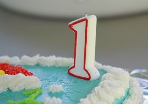 Detalhe de bolo de aniversário azul com vela de 1 ano no canto. Fonte: Pixabay